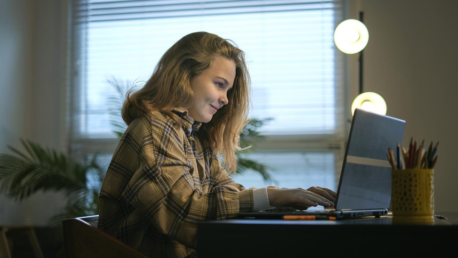 Student working on a laptop with a notebook while planning online work